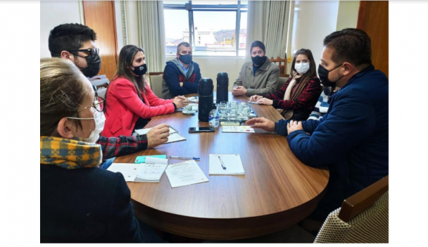 Imagem de pessoas reunidas em volta de uma mesa oval
