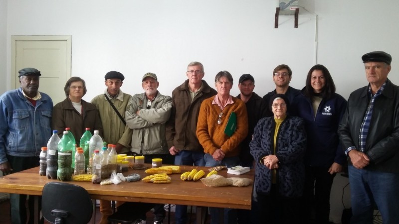 Foto com pessoas atrás de uma mesa com comidas em cima.