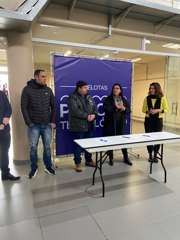 Pessoas atrás de uma mesa assinando um termo.