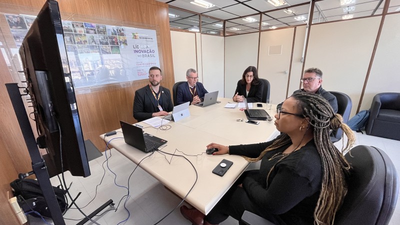 Foto das pessoas em volta da mesa olhando o computador