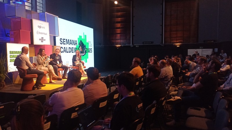 Imagem mostra painelistas em frente &agrave; plateia.