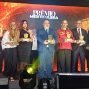Premiados no palco com prêmios em mãos posam para foto.