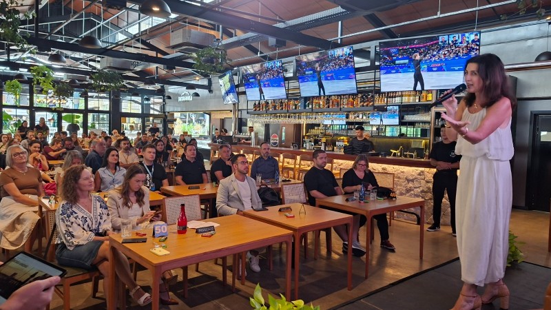 mulher num palco de frente para o p&uacute;blico, com microfone na m&atilde;o.